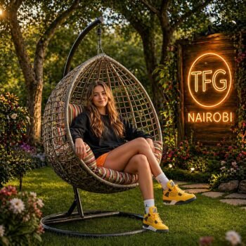 A happy client sitting comfortably in a SERENGETI LB188-MCS hanging egg chair with multi-color striped cushions, relaxing in a beautiful garden at a villa in Mimosa, Runda.