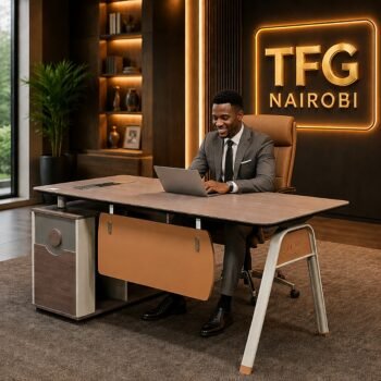 A male diplomat in a grey suit working on a laptop at a SESSI YT55 1.6m executive office desk with tan leather accents in a luxury Gigiri office.
