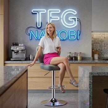 A smiling lady in a white top and pink skirt sitting comfortably on a modern gray A226 quilted leather swivel bar stool at a kitchen island in Mimosa, Runda, Nairobi.
