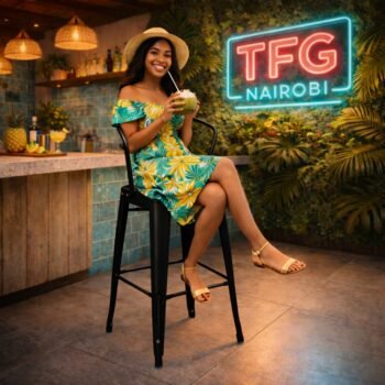 A smiling lady in a tropical floral dress enjoying a coconut drink while seated on a matte black HFB-4088 metallic bar stool at a modern kitchen island in Runda, Nairobi.