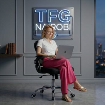 A professional German technocrat in a white shirt and pink trousers working on a laptop while seated on an FT718 ergonomic mid-back mesh office chair in a Gigiri Nairobi office.