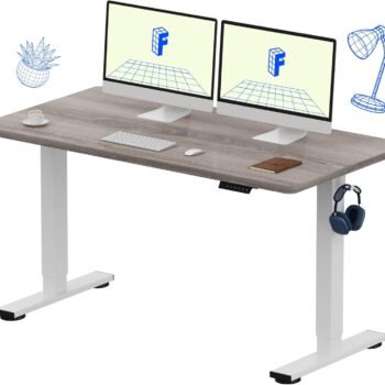 FlexiSpot EN1GW 1.4M Electric Height Adjustable Standing Desk in Grey Wood Grain finish with dual monitor setup and white motorized frame in a Loresho Ridge home office.