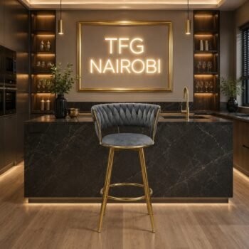 Luxury H-1871 bar chair with high-polished gold legs standing in a premium modern kitchen in Hurlingham under a glowing neon TFG NAIROBI sign.